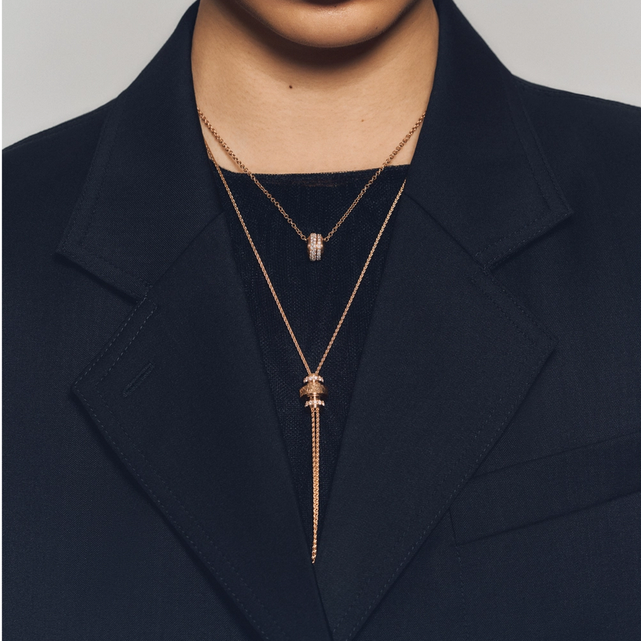 Front-facing portrait of a woman wearing a dark blazer, styled with minimalist gold hoop earrings and layered rose gold necklaces from the Piaget Possession collection, featuring pavé diamond accents.