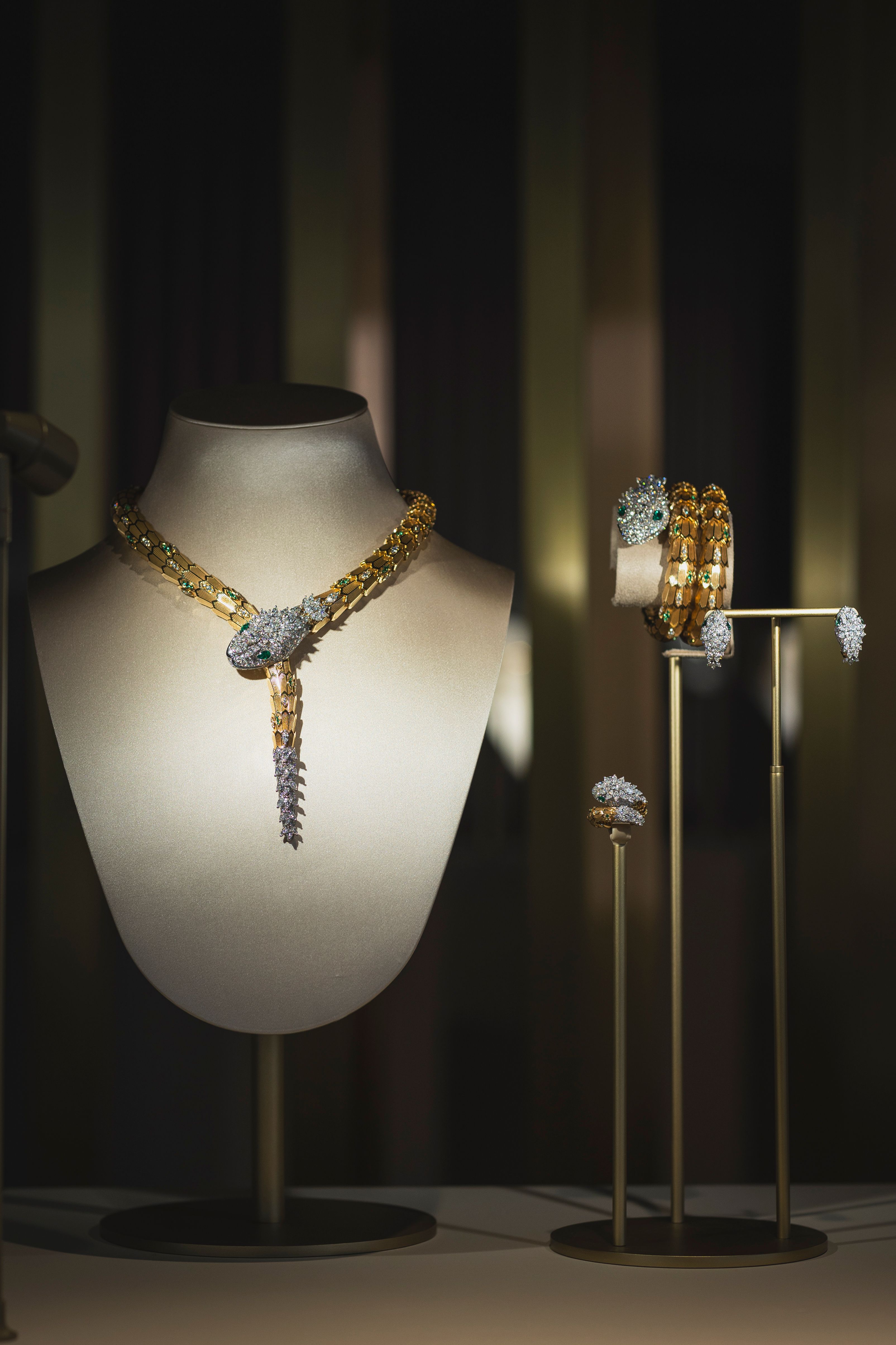 High jewelry display featuring dazzling Bulgari necklaces, rings, and bracelets, showcased on elegant busts under focused lighting.