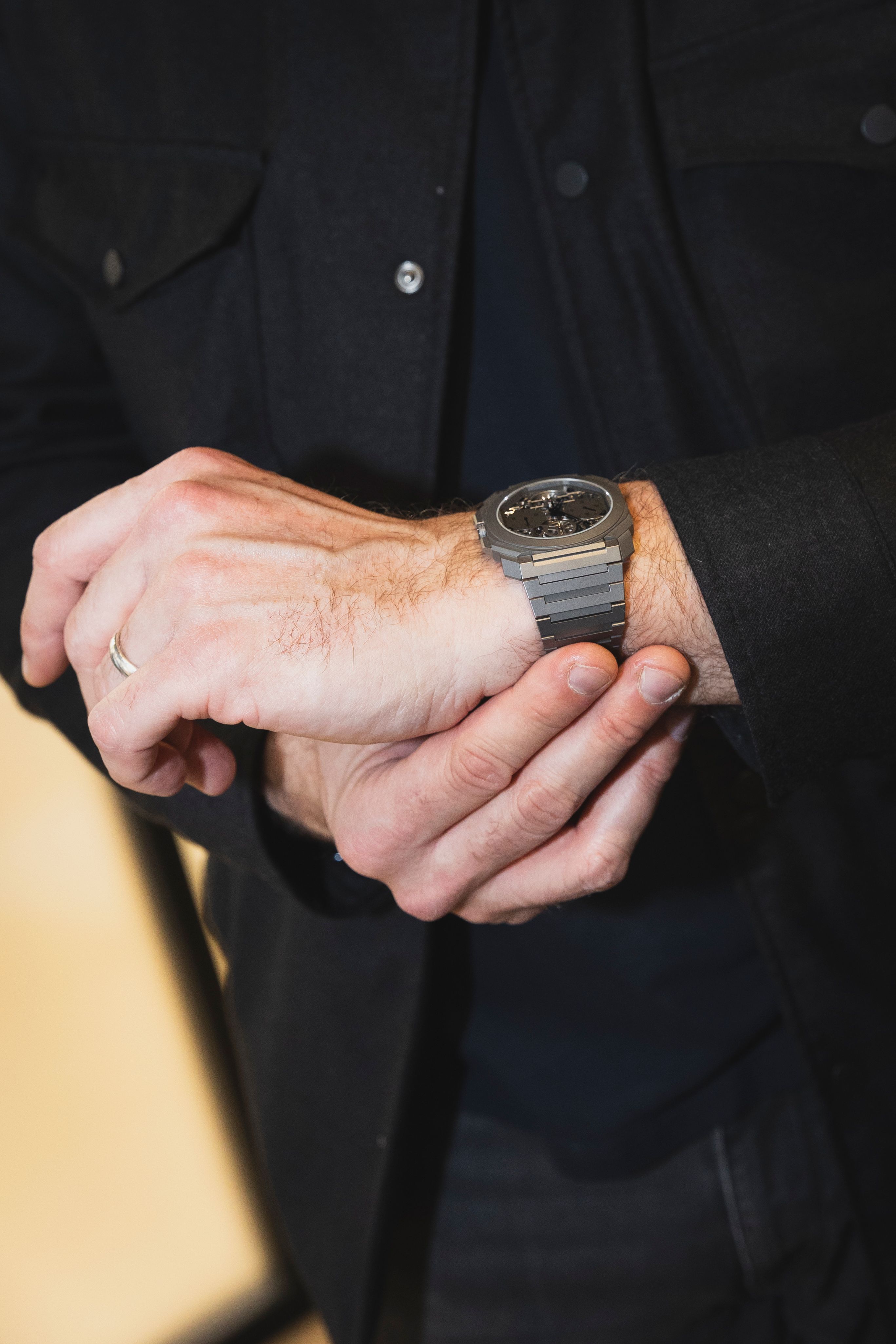 Close-up of a man adjusting a Bulgari Octo Finissimo watch on his wrist, showcasing the sleek and contemporary titanium design.