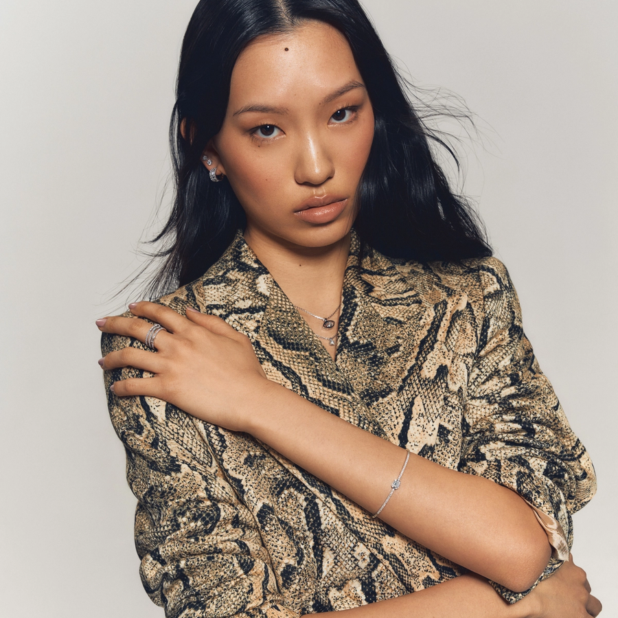 Portrait of a woman wearing a snakeskin-patterned blazer, styled with diamond earrings, a delicate pavé bracelet, stacked rings, and a pendant necklace from Château D’Ivoire’s signature collections.