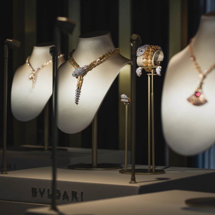High jewelry display featuring dazzling Bulgari necklaces, rings, and bracelets, showcased on elegant busts under focused lighting.