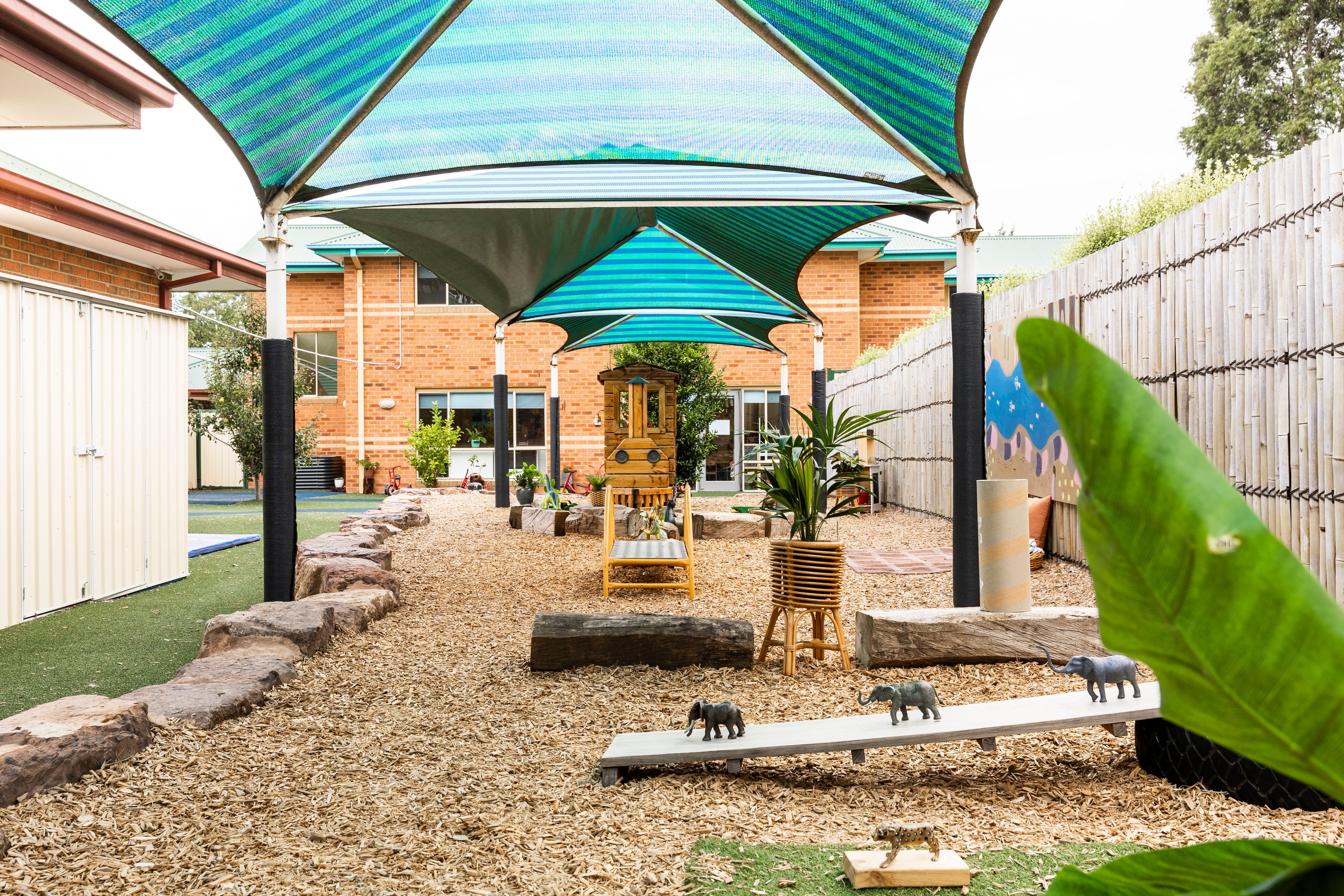 A shaded playground with plants and toys