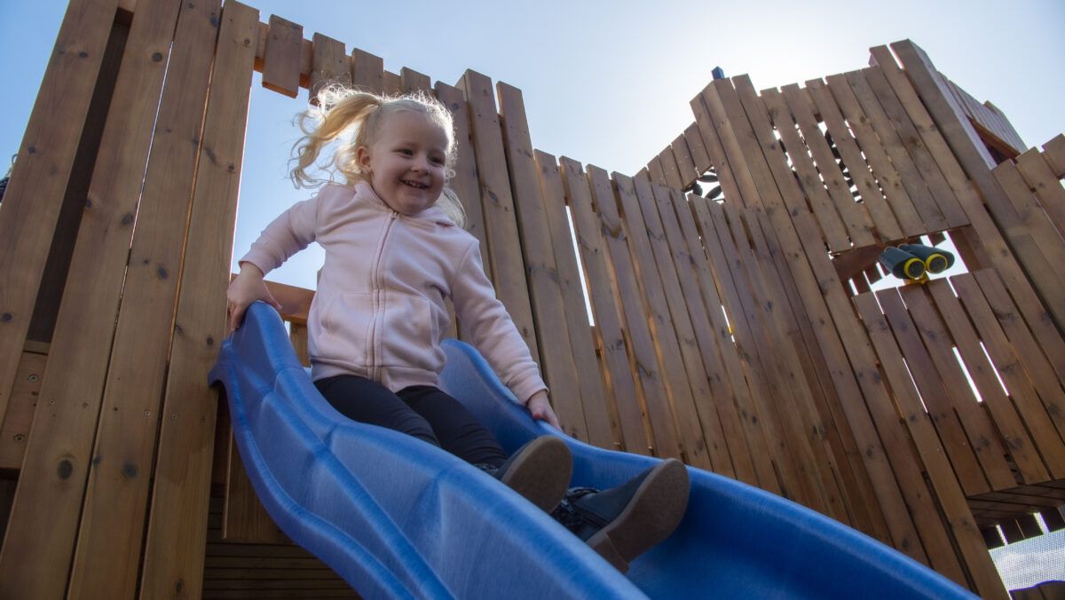 A young girl goes down a blue slide