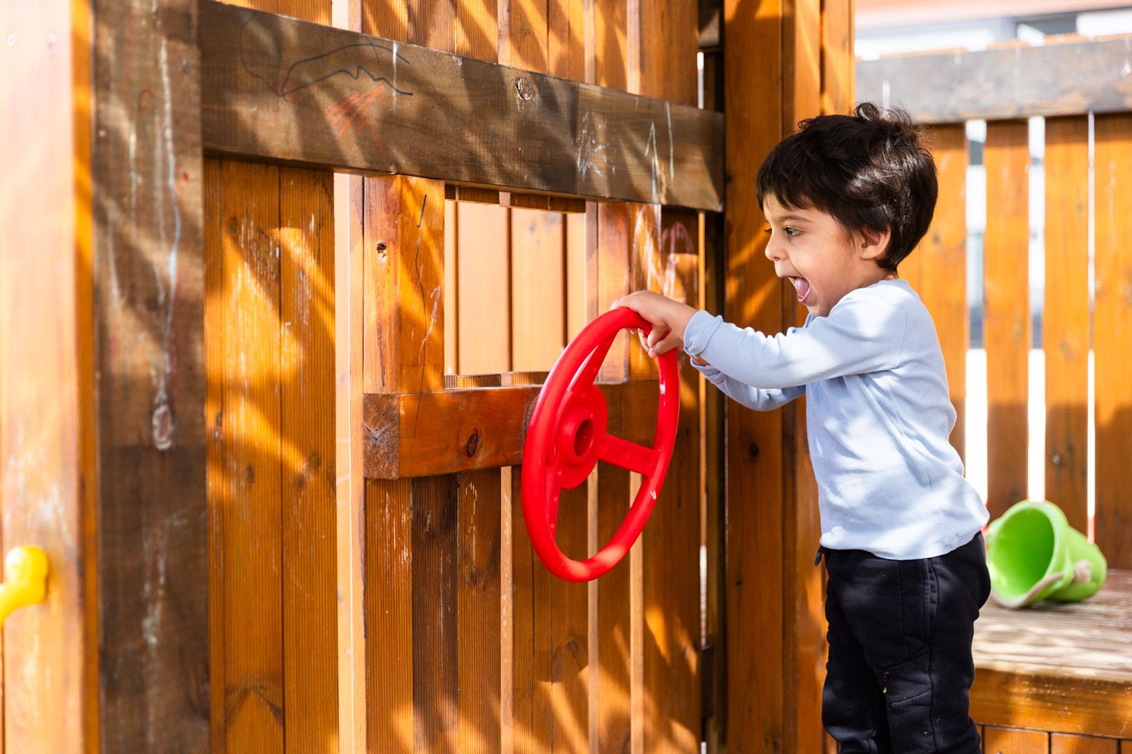 Young children and an educator play in a sandpit