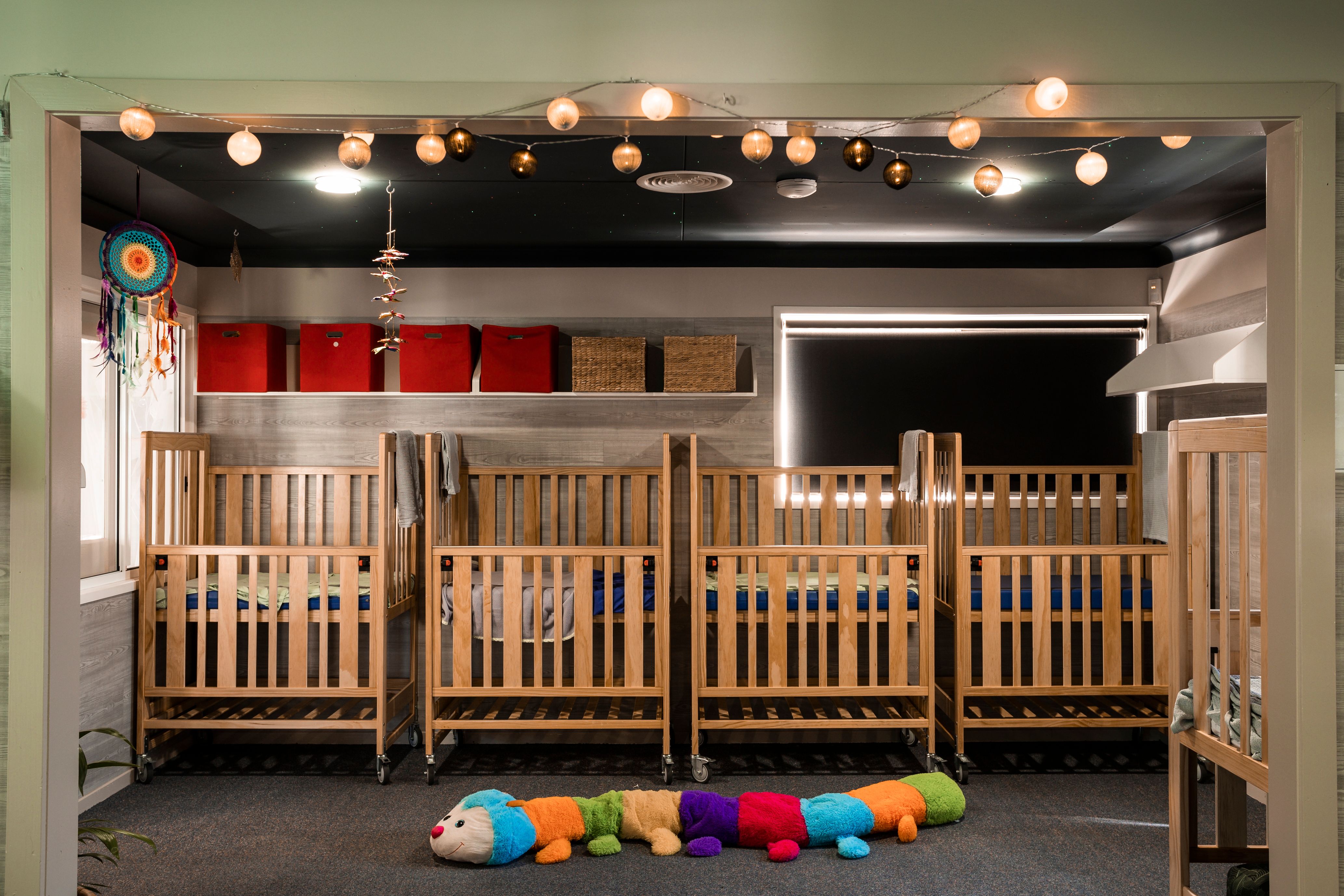 A cosy sleep room with cots and low lighting