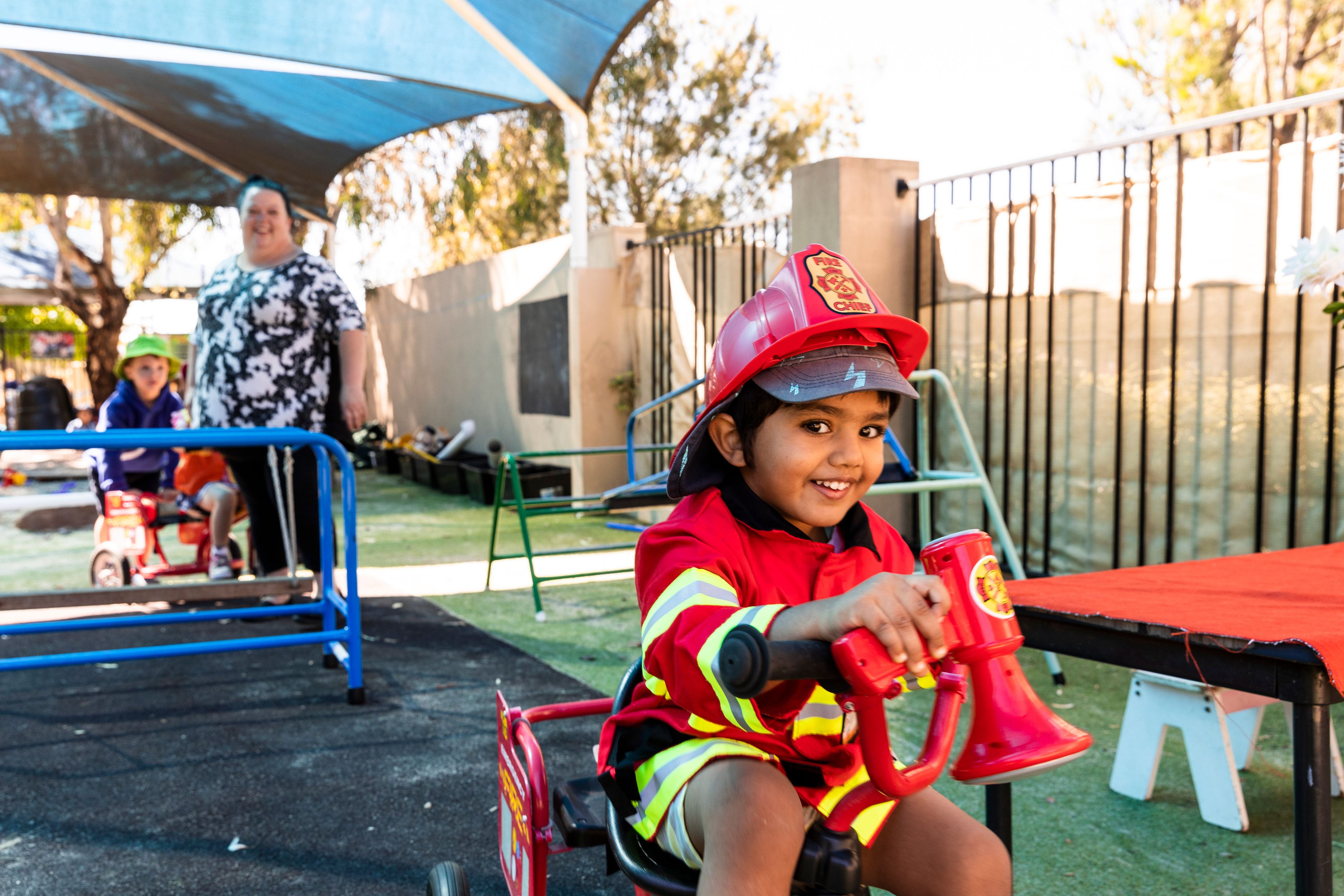 A young child dressed as a firefighter plays