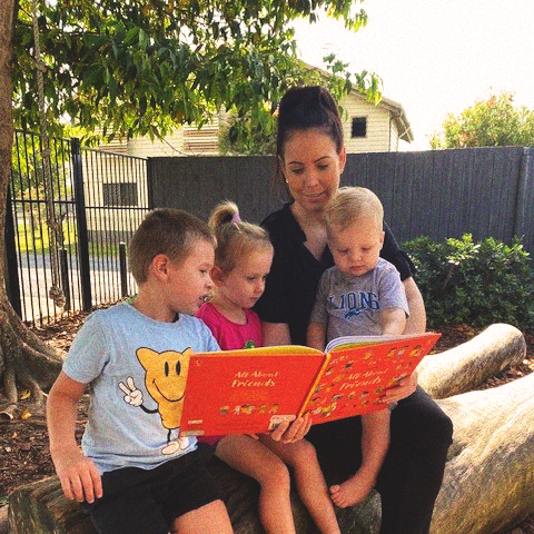An educator reading to three young children