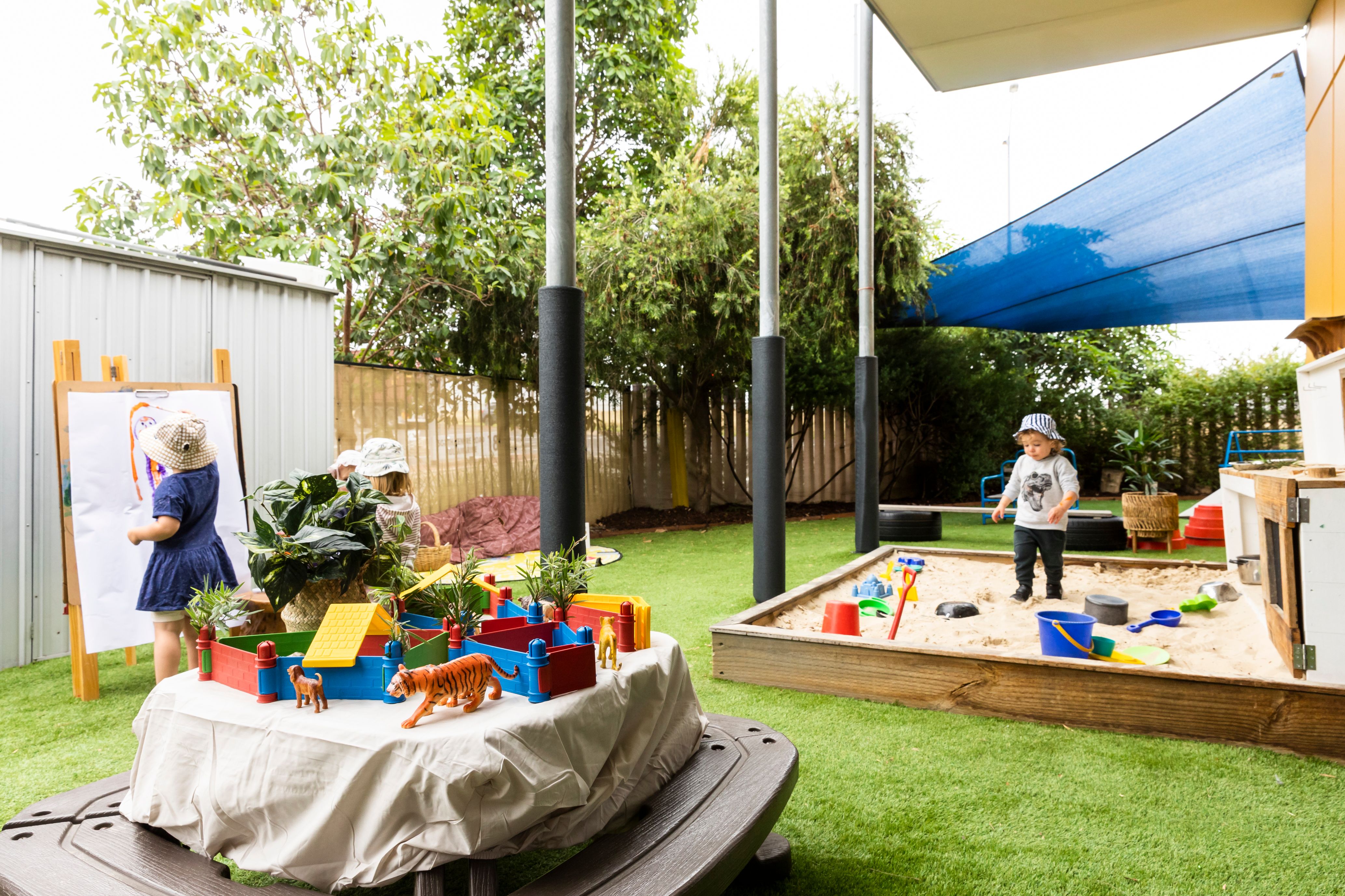 Children in a sandpit and a painting outdoors