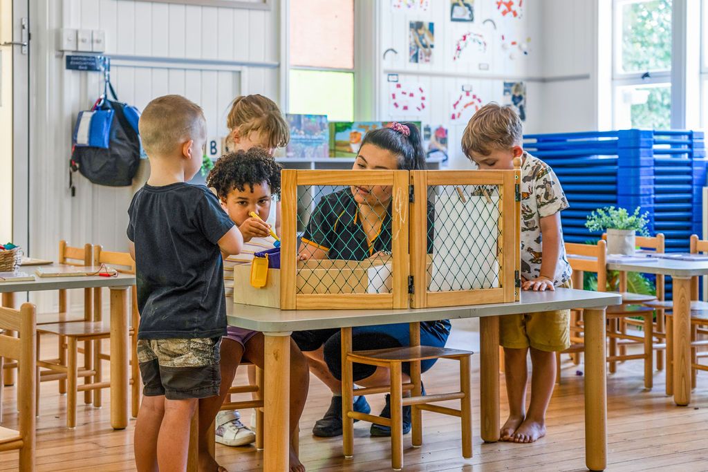 Young children and an educator gathered around a table learning