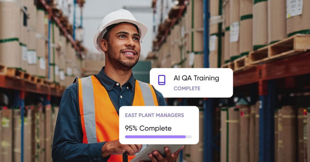 A man wearing a white hard hat and an orange safety vest is standing in a warehouse filled with stacked boxes on shelves. He is holding a tablet and looking slightly upward with a smile. Overlaid text boxes show "AI QA Training COMPLETE" and "EAST PLANT MANAGERS 95% Complete" with a progress bar.
