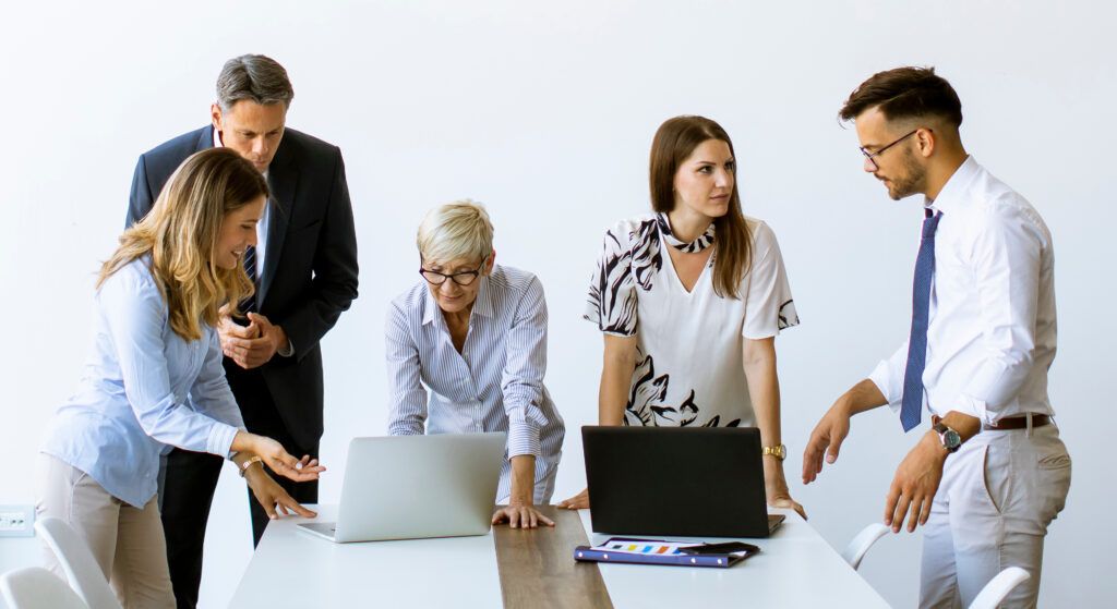 Group of business people with young adults and senior woman colleague on meeting at the modern bright office interior