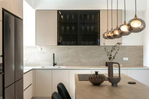 Moderne lichte keuken met een hoge rvs-koelkast, een kookeiland en hanglampen.