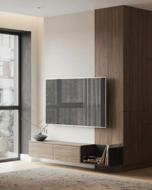 Rustige woonkamer met een zwevend tv-meubel van licht hout onder een tv aan een witte wand, naast een walnoothouten kastwand.