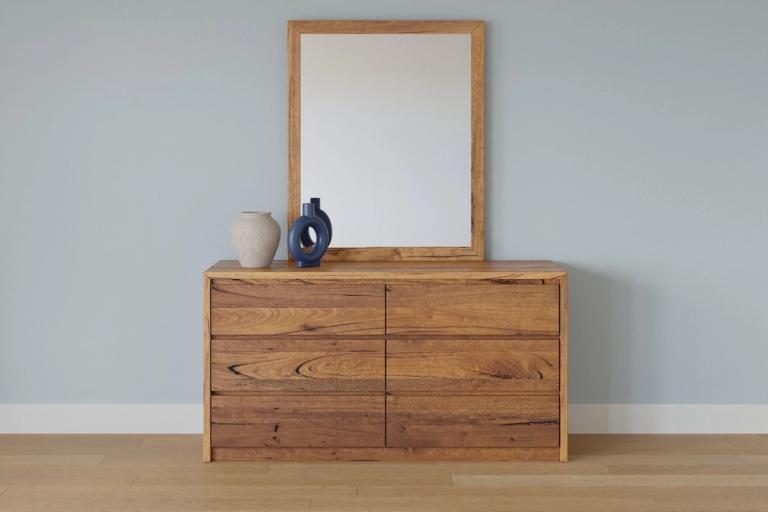 Wooden dresser with a mirror and two vases on top, against a light blue wall.