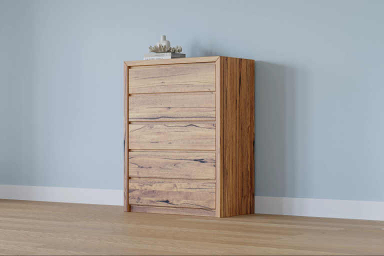 A five-drawer natural wood dresser with dark grain accents against a light blue wall.