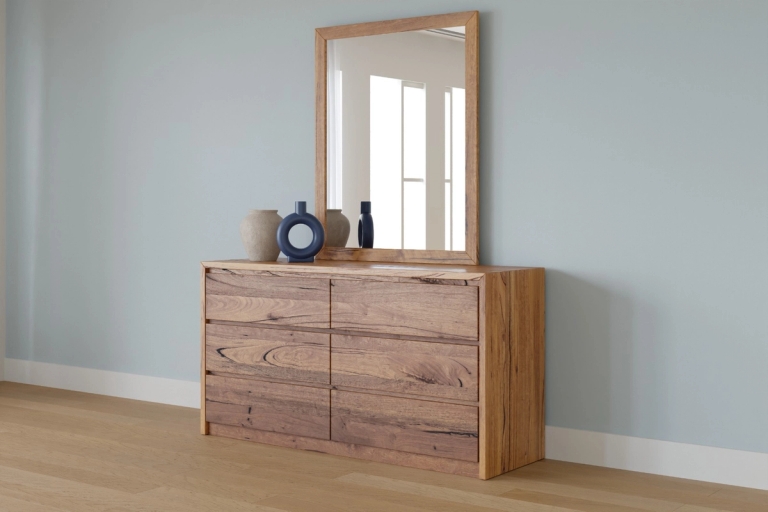 Wooden six-drawer dresser with a matching mirror and decorative vases against a light blue wall.