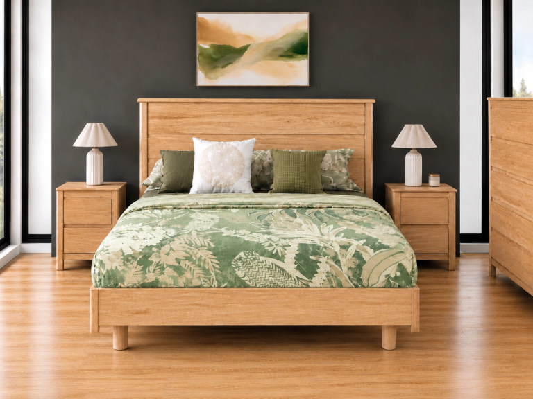 A bedroom with a light wood bed, green patterned bedding, matching nightstands with lamps, and a landscape painting on a dark gray wall.