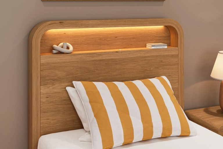Wooden headboard with an illuminated shelf, a yellow and white striped pillow, and a bedside lamp.