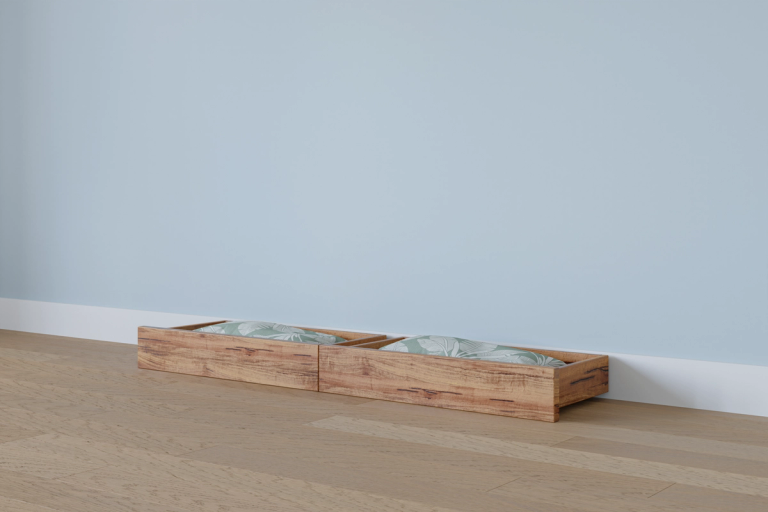 Two wooden storage boxes with green patterned fabric inside, on a wooden floor against a light blue wall.