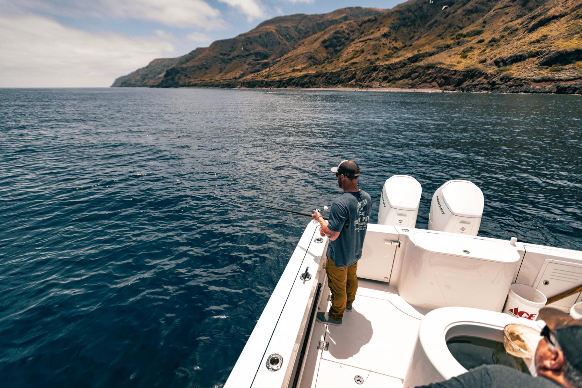 Fisherman jigs off the starboard side of Lindell 41 with island cliffs in the background
