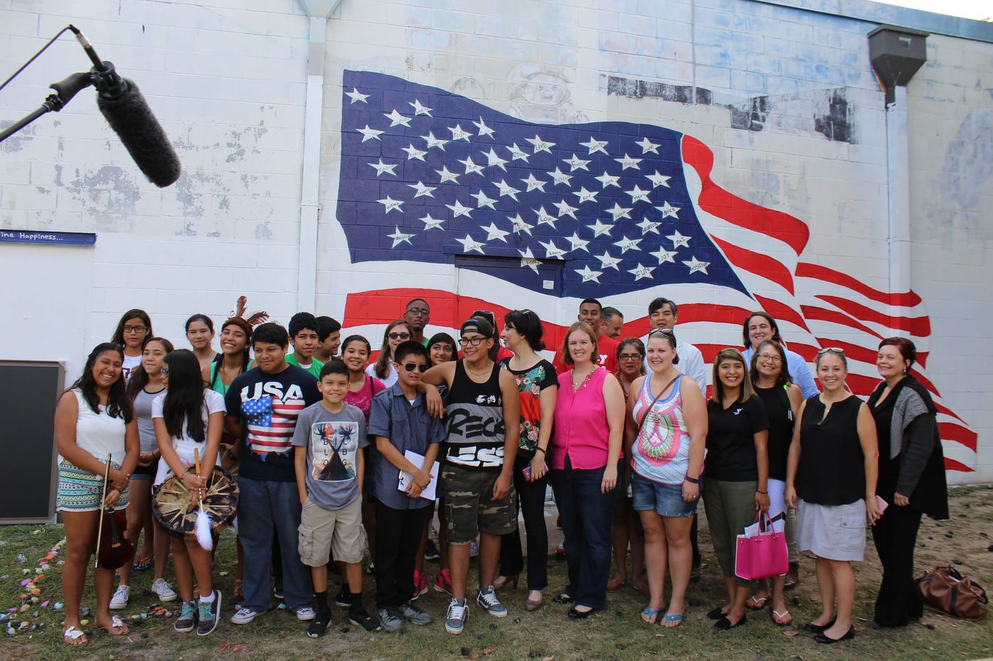 Young people and facilitators gathered in front of a painted flag mural