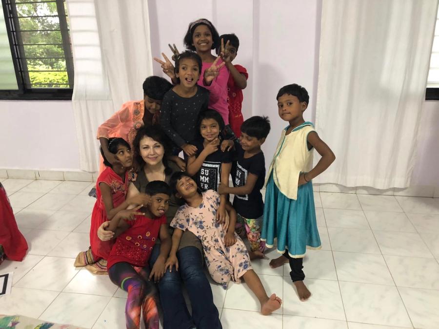 Karine Parker sitting on the floor with a group of smiling girls at Grace House India
