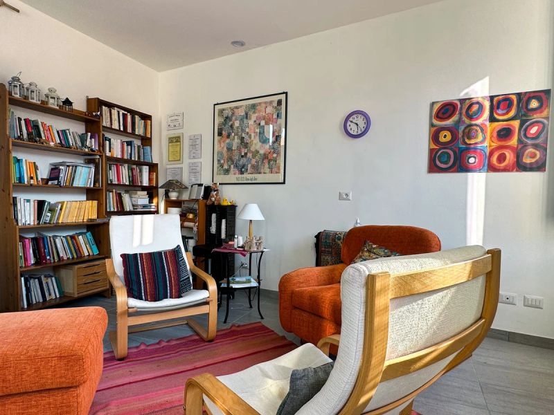 Angolo dello studio con libreria piena di libri, poltrone e un quadro di Kandinsky alla parete.