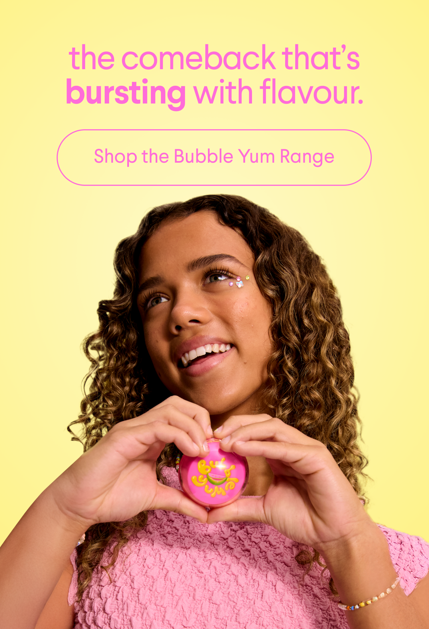 a girl in a pink shirt is holding a pink bubble yum in her hands