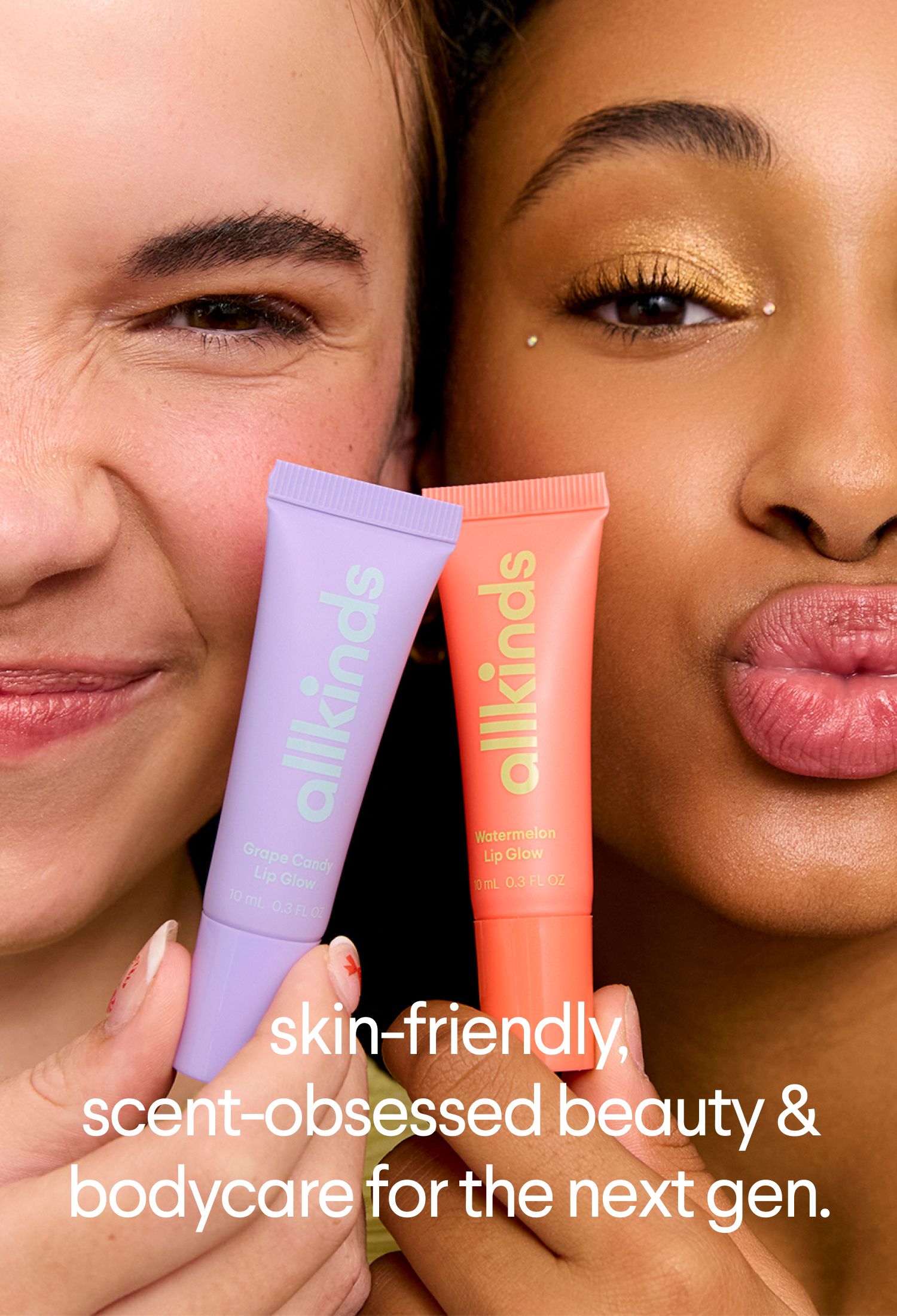 Close-up of two women: one light-skinned smiling, the other dark-skinned with gold glitter eyeshadow making a kissy face. Both hold "all kinds" lip gloss tubes.
