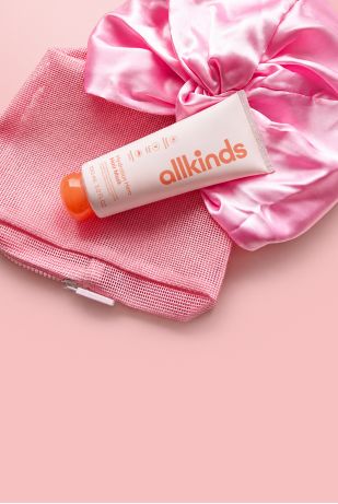 alllkinds Hydration Hero Hair Mask tube, a pink mesh bag, and a pink satin scrunchie.