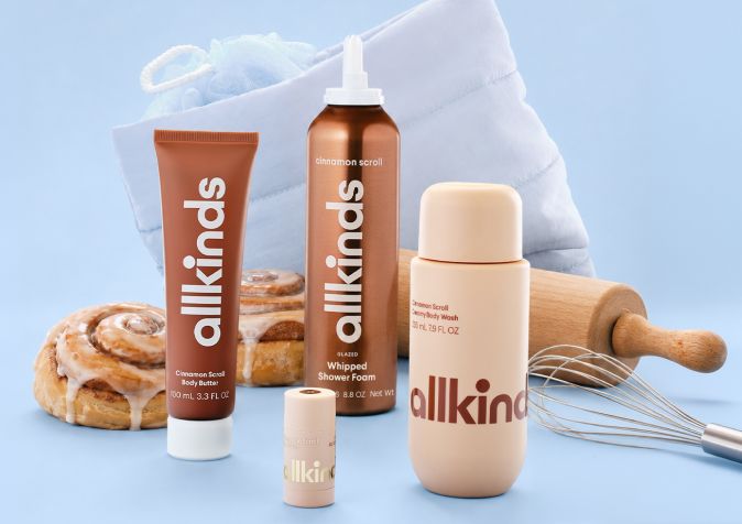 Allkinds cinnamon scroll body butter, shower foam, and body wash with cinnamon rolls, a rolling pin, whisk, and loofah.