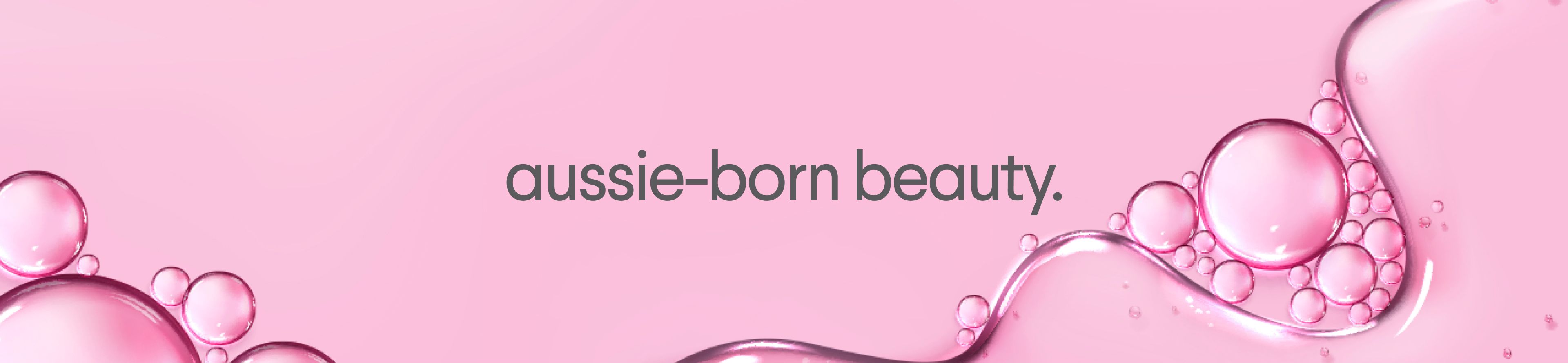 Pink background with translucent bubbles and liquid, featuring the text 'aussie-born beauty.'