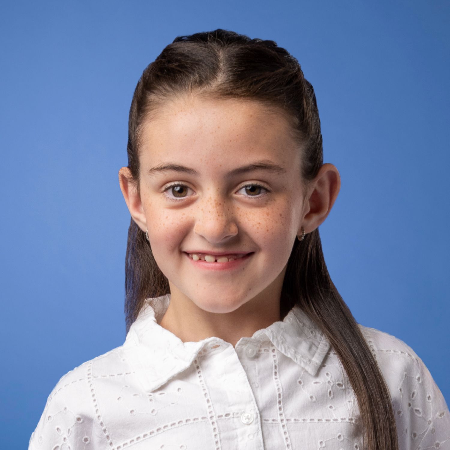 the girl is wearing a white shirt and smiling for the camera .