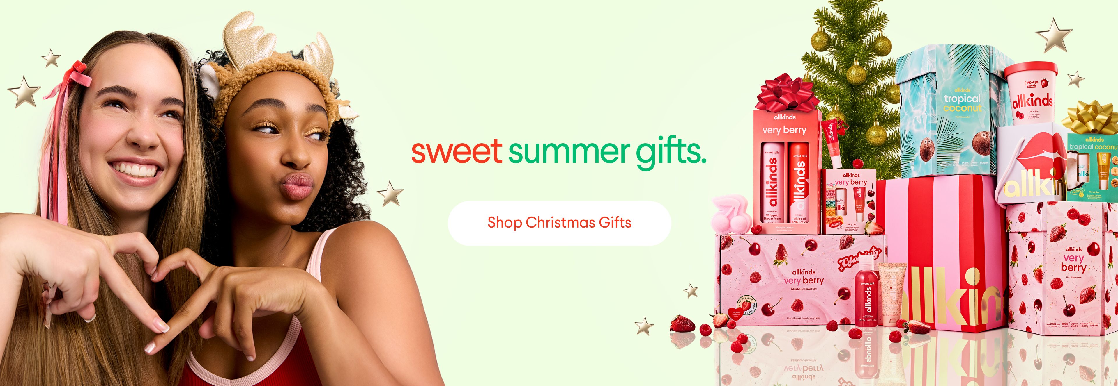 Two young women making a heart, text "sweet summer gifts." and "Shop Christmas Gifts," with a stack of festive gifts and a small Christmas tree.
