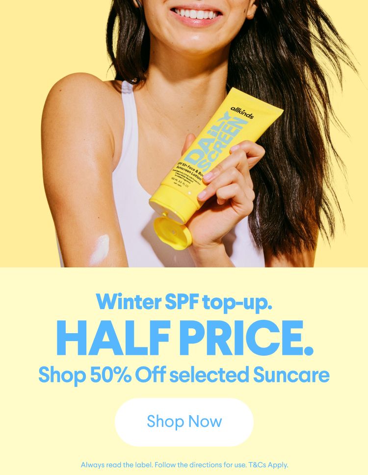 A smiling woman applies allkinds Daily Screen SPF 50+ sunscreen to her arm. Text: Winter SPF top-up. HALF PRICE. Shop 50% Off selected Suncare.