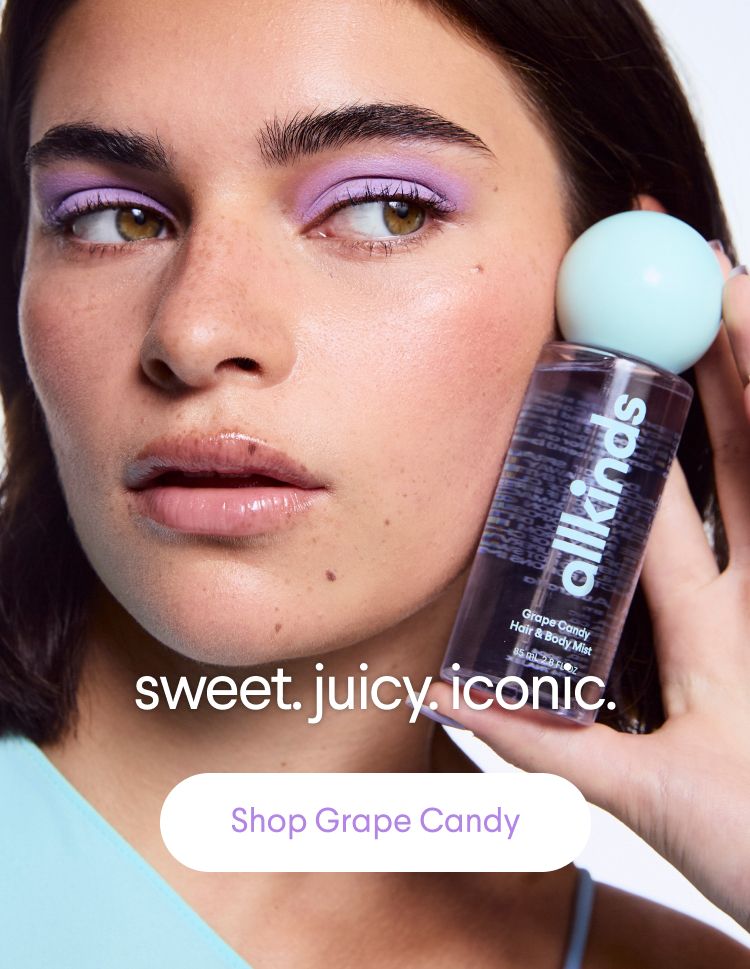 A woman with purple eyeshadow and glossy lips holds an allkinds Grape Candy Hair & Body Mist. Text: "sweet. juicy. iconic. Shop Grape Candy."