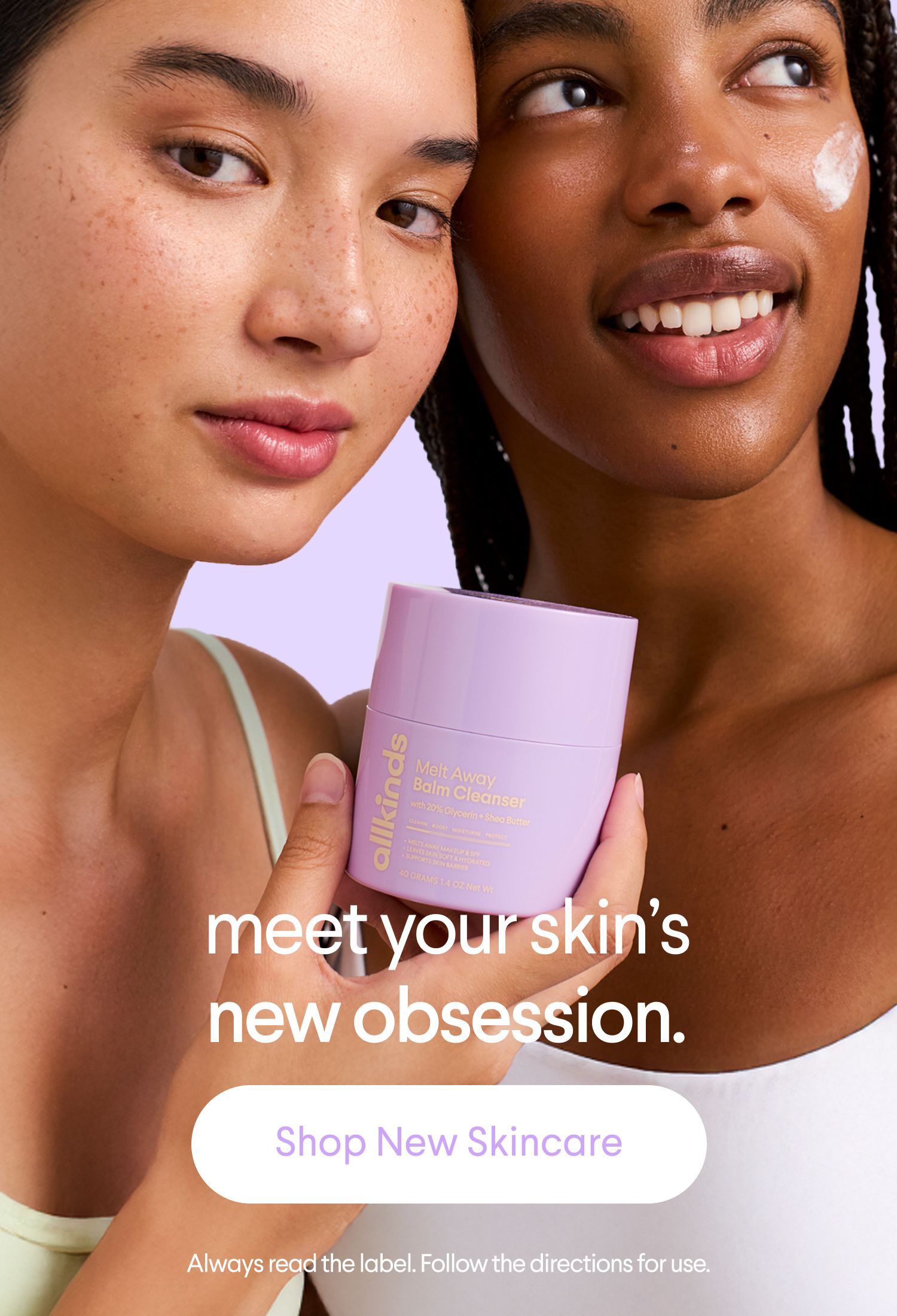 Two women, one with freckles and one with dark skin, stand close together. The freckled woman holds a lavender "allkinds Melt Away Balm Cleanser" jar. The other woman has a dab of white product on her cheek and smiles. Text reads "meet your skin's new obsession." and a button "Shop New Skincare."