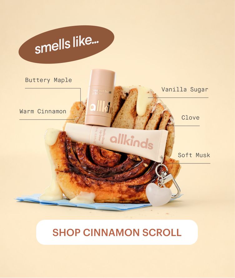 Allkinds Cinnamon Scroll lip glaze and stick product on a frosted cinnamon scroll. Text 'smells like...' lists notes: Buttery Maple, Warm Cinnamon, Vanilla Sugar, Clove, Soft Musk. 'Shop Cinnamon Scroll' button.