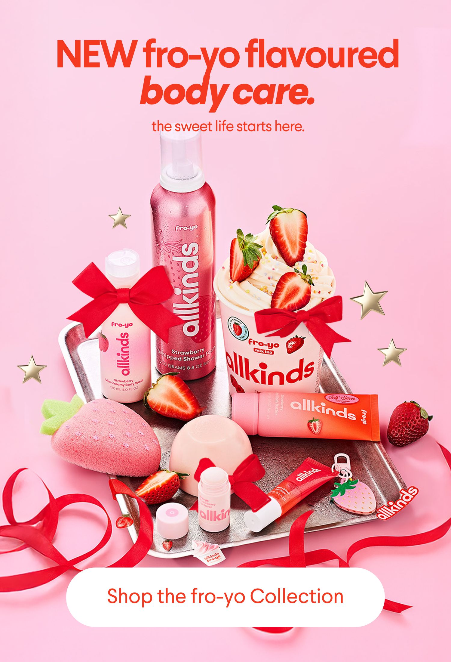 New Allkinds fro-yo flavoured body care products, including body wash, shower foam, and bath bombs, arranged on a tray with strawberries and ribbons. Text: "NEW fro-yo flavoured body care. Shop the fro-yo Collection."