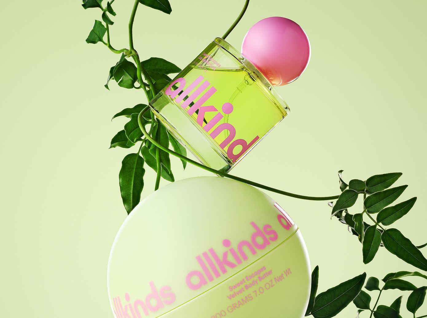 A clear bottle of green 'allkind' perfume with a pink cap balances on a spherical light green 'allkinds' body butter, surrounded by green vines on a pale green background.