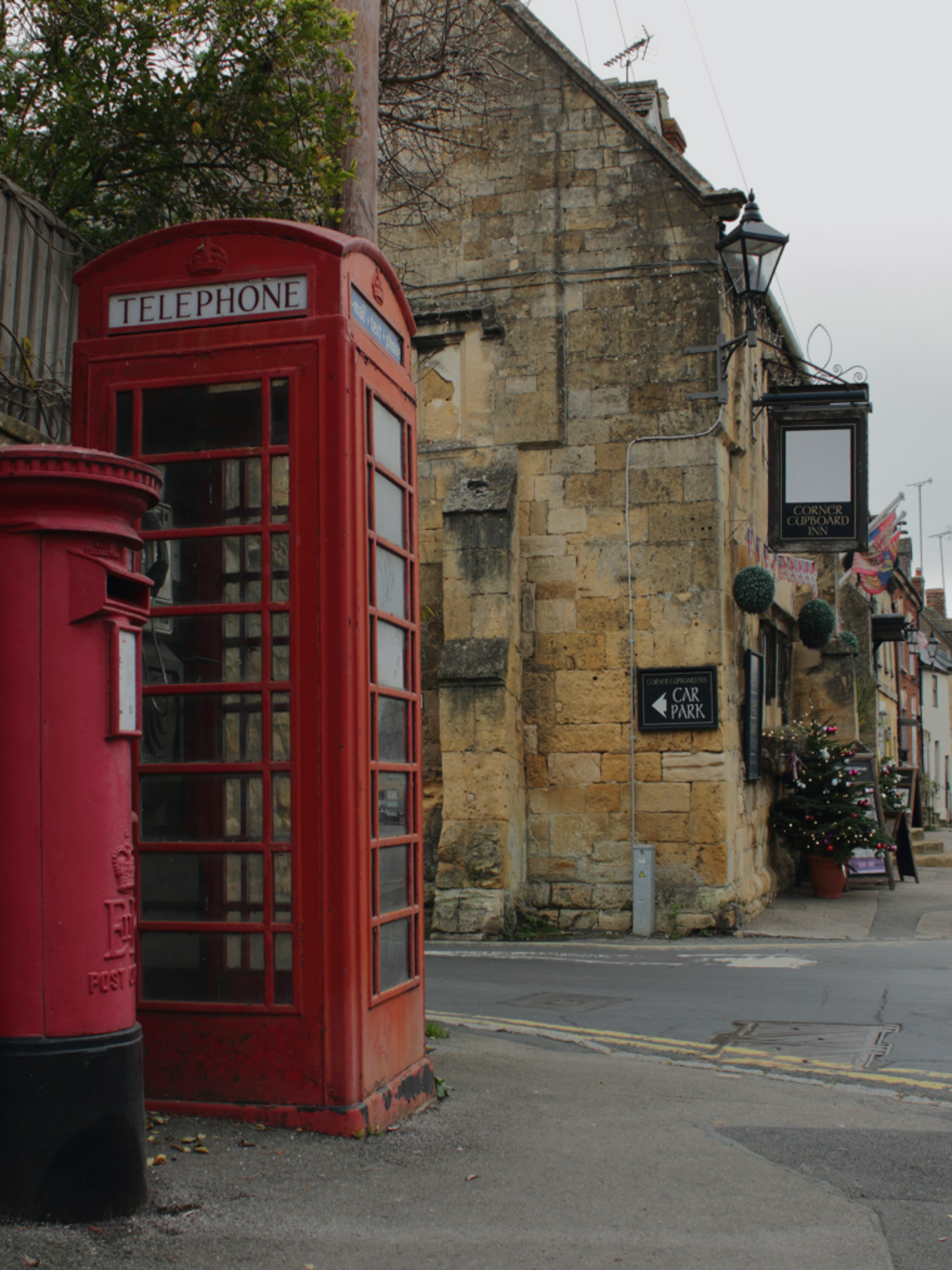 A red telephone box and post box on a village street