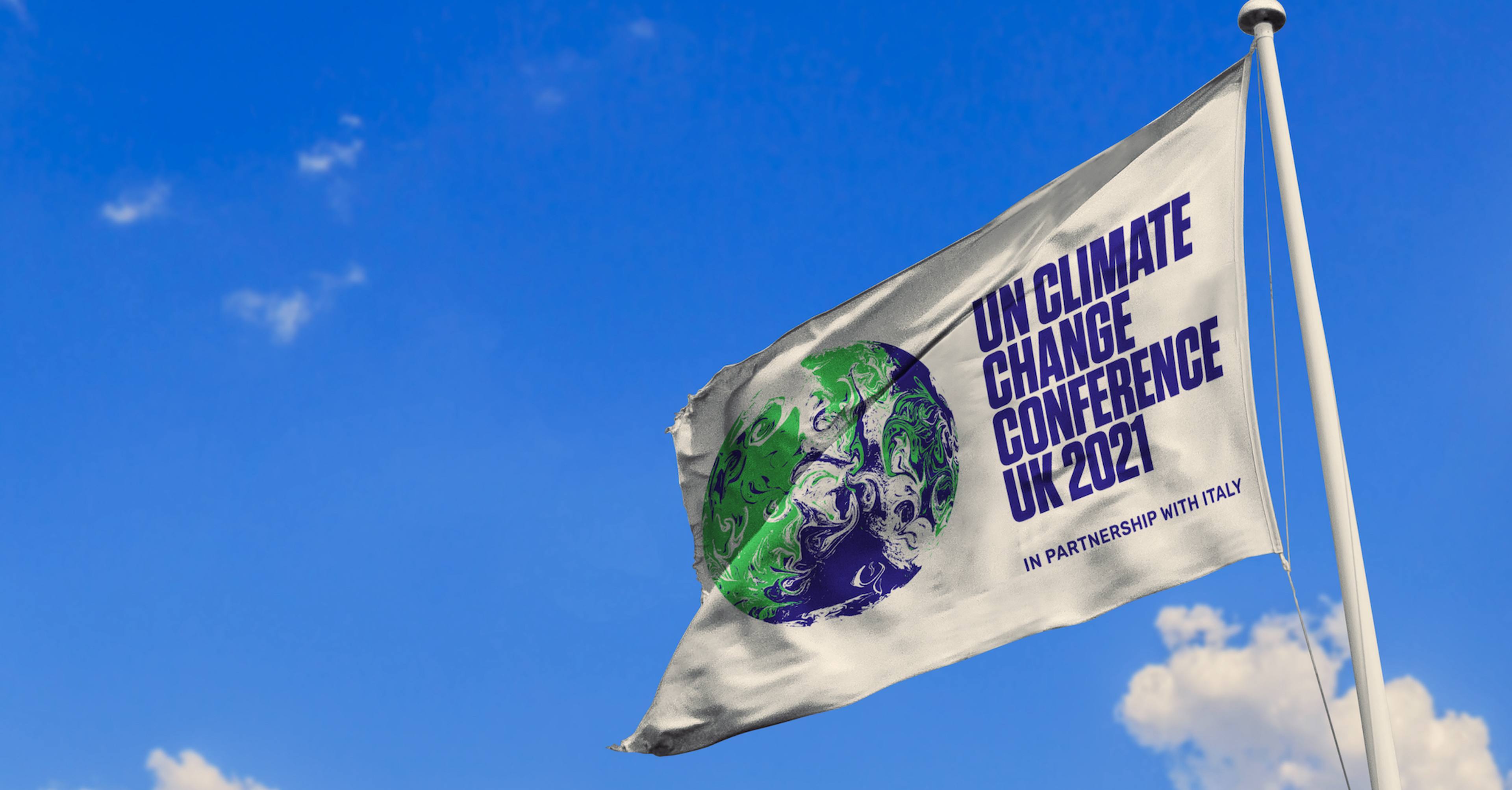 UN Climate Conference flag flying at the top of a flagpole in front of a bright blue sky