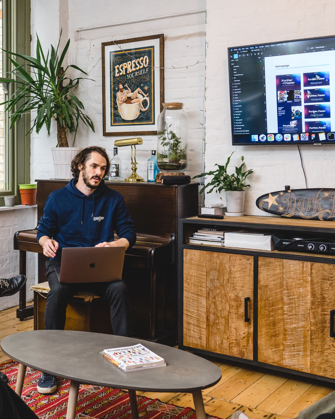 A team member presenting from a laptop in the studio's lounge, a screen on the wall beside them. AI consultancy, AI & Emerging Technology.