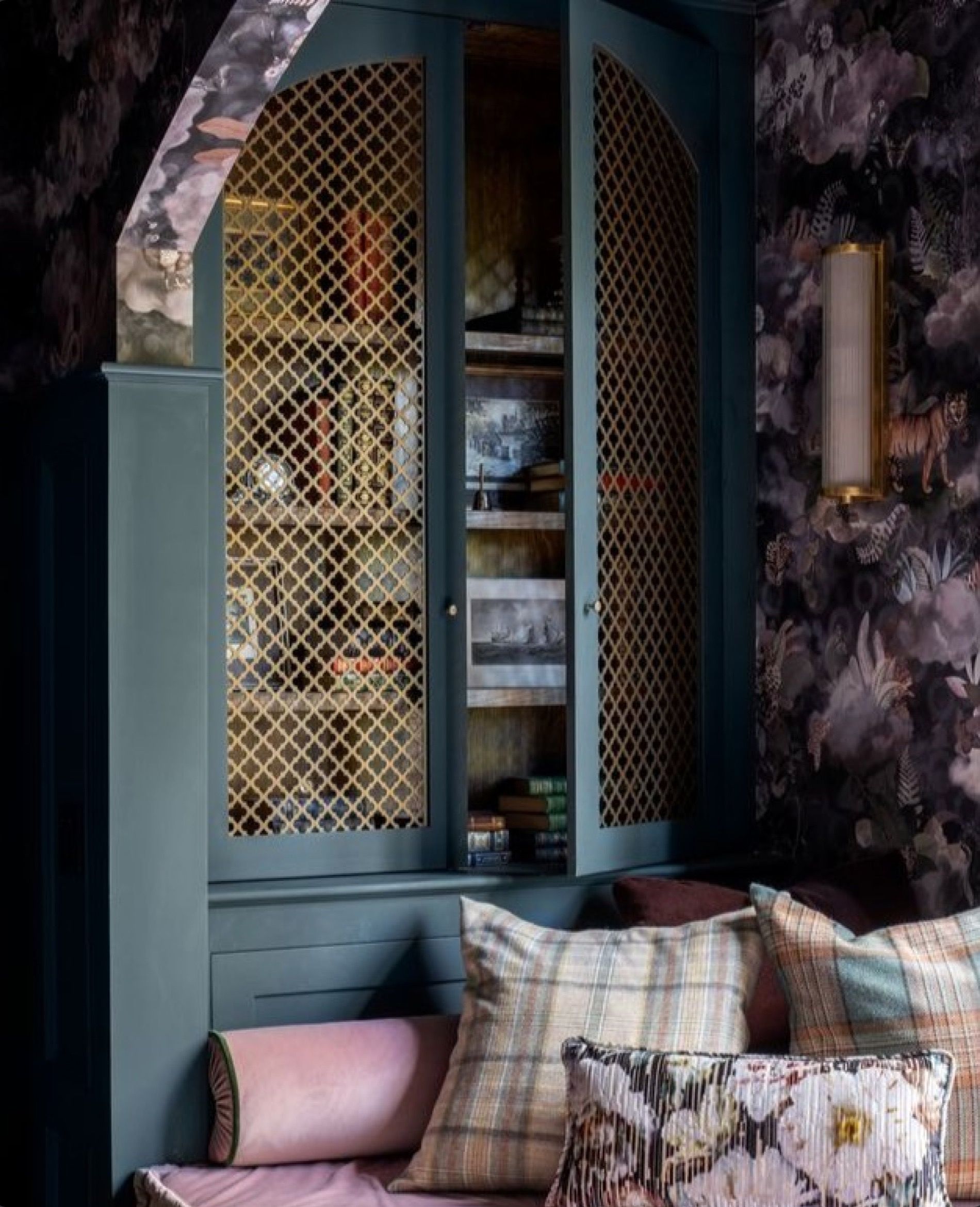 A brass grille set into a green cabinet door