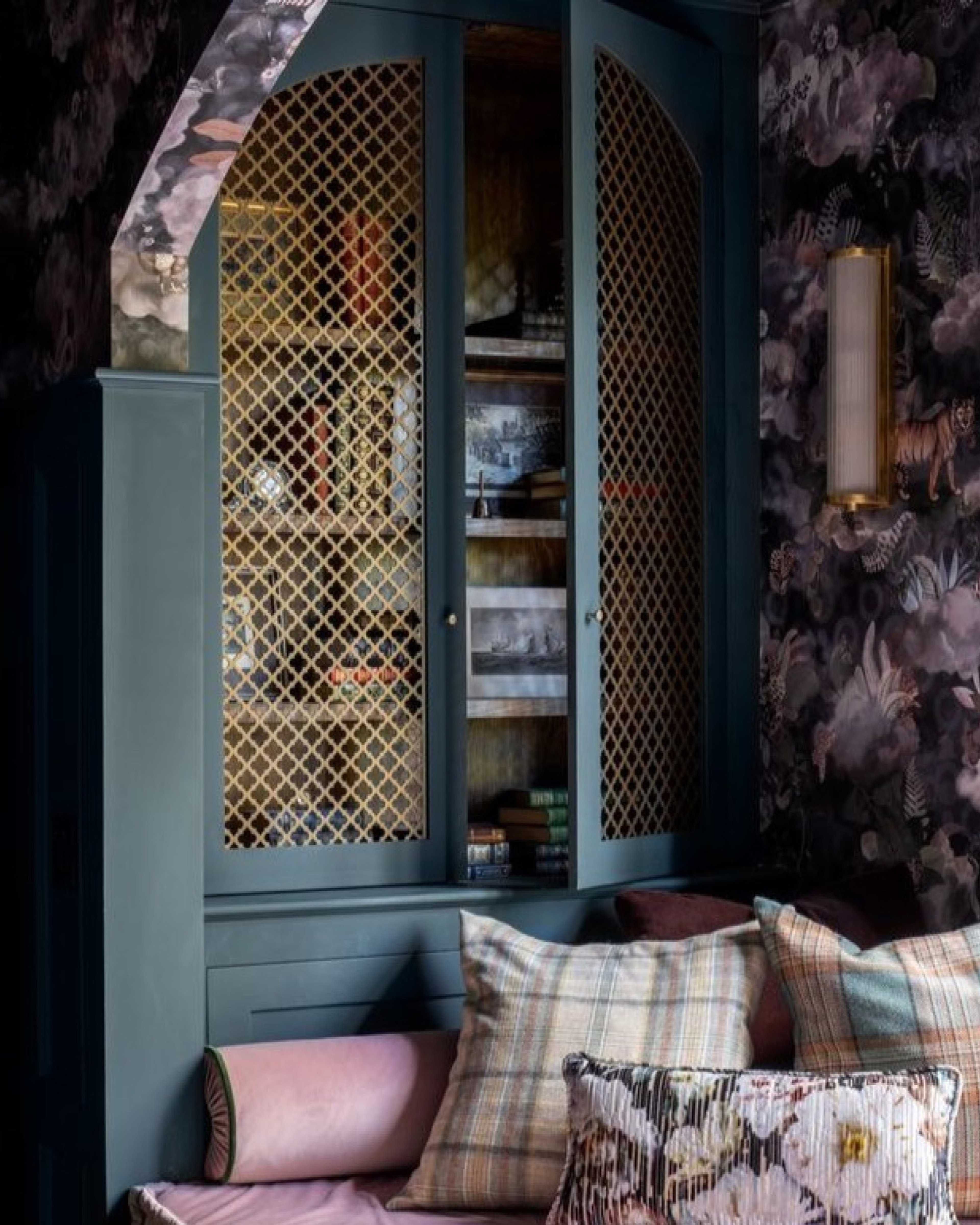 A brass grille set into a green cabinet door