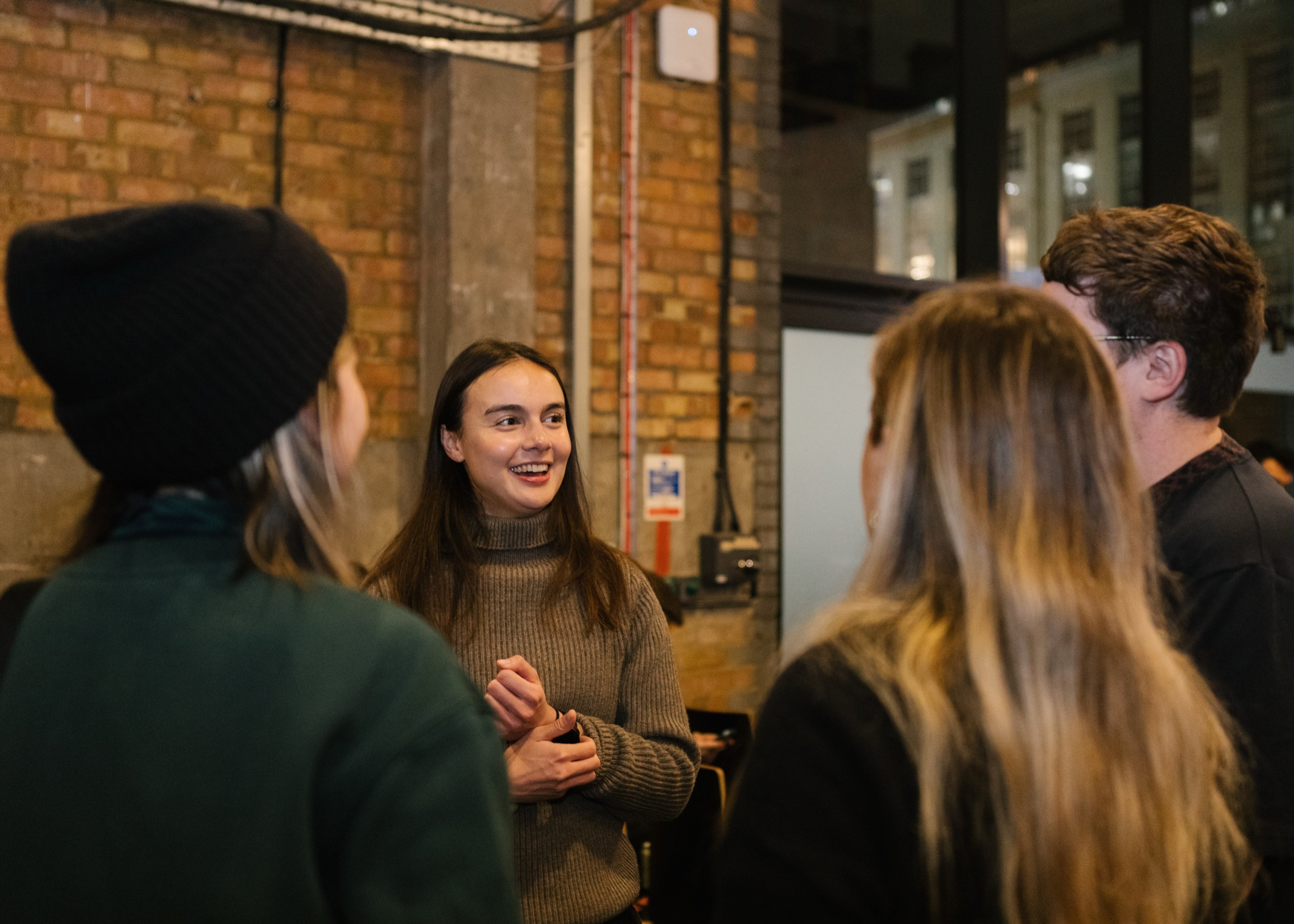 A group of guests talking in a brick-walled room