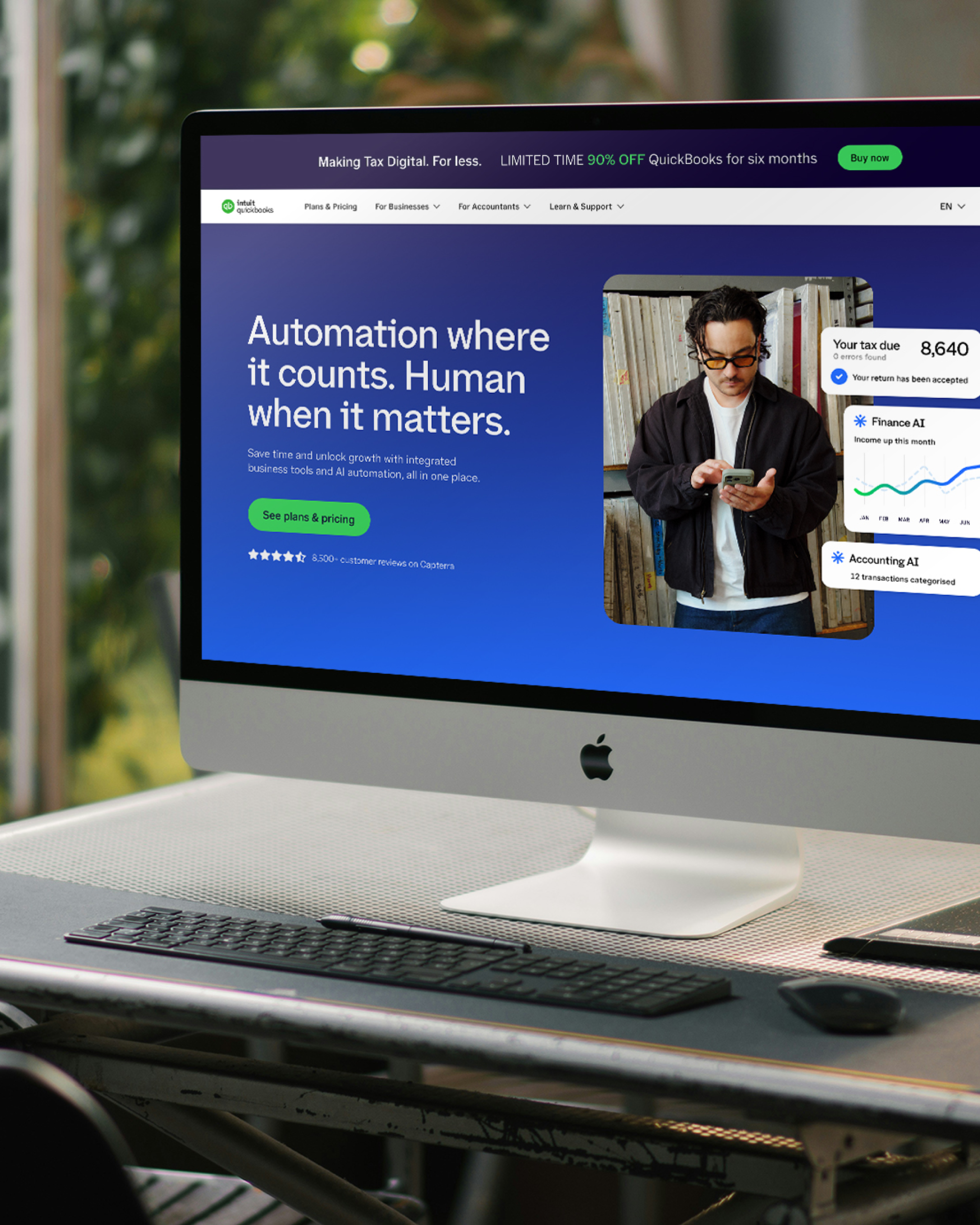 An iMac on a desk showing the redesigned QuickBooks homepage