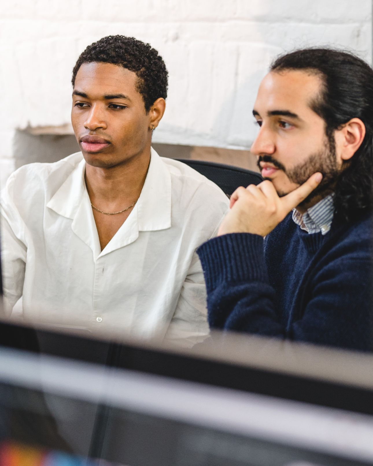 Two team members studying a screen together, one resting their chin on their hand. Product design, Experience Design.