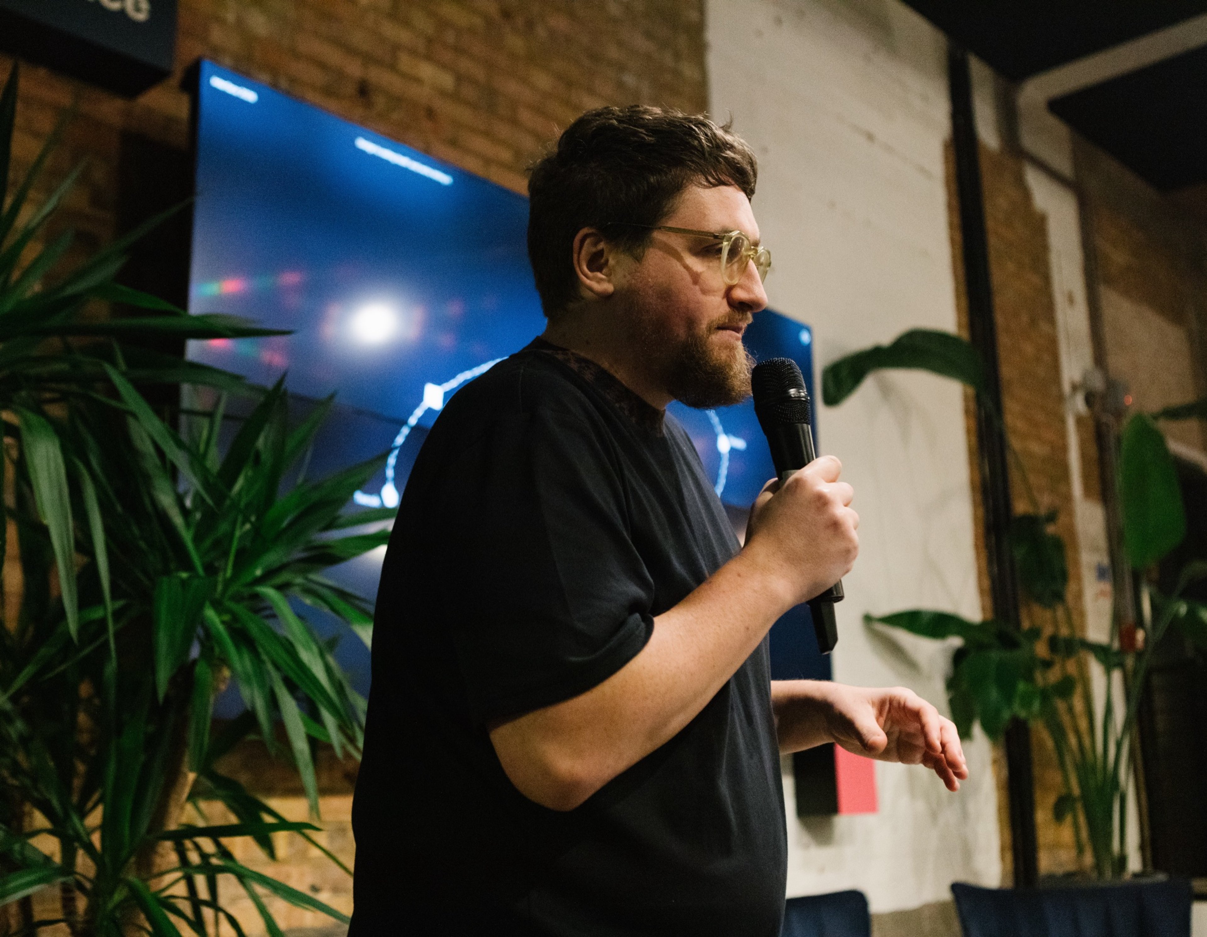 A speaker with a microphone presenting in front of a screen