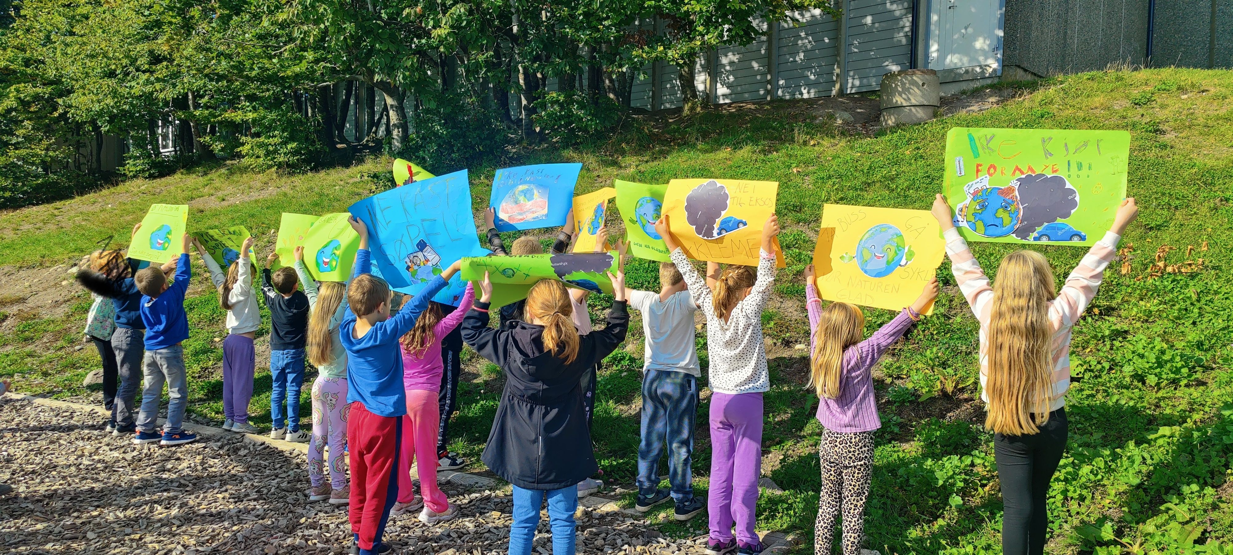 En skoleklasse har laget plakater. Alle barna står med ryggen til. 